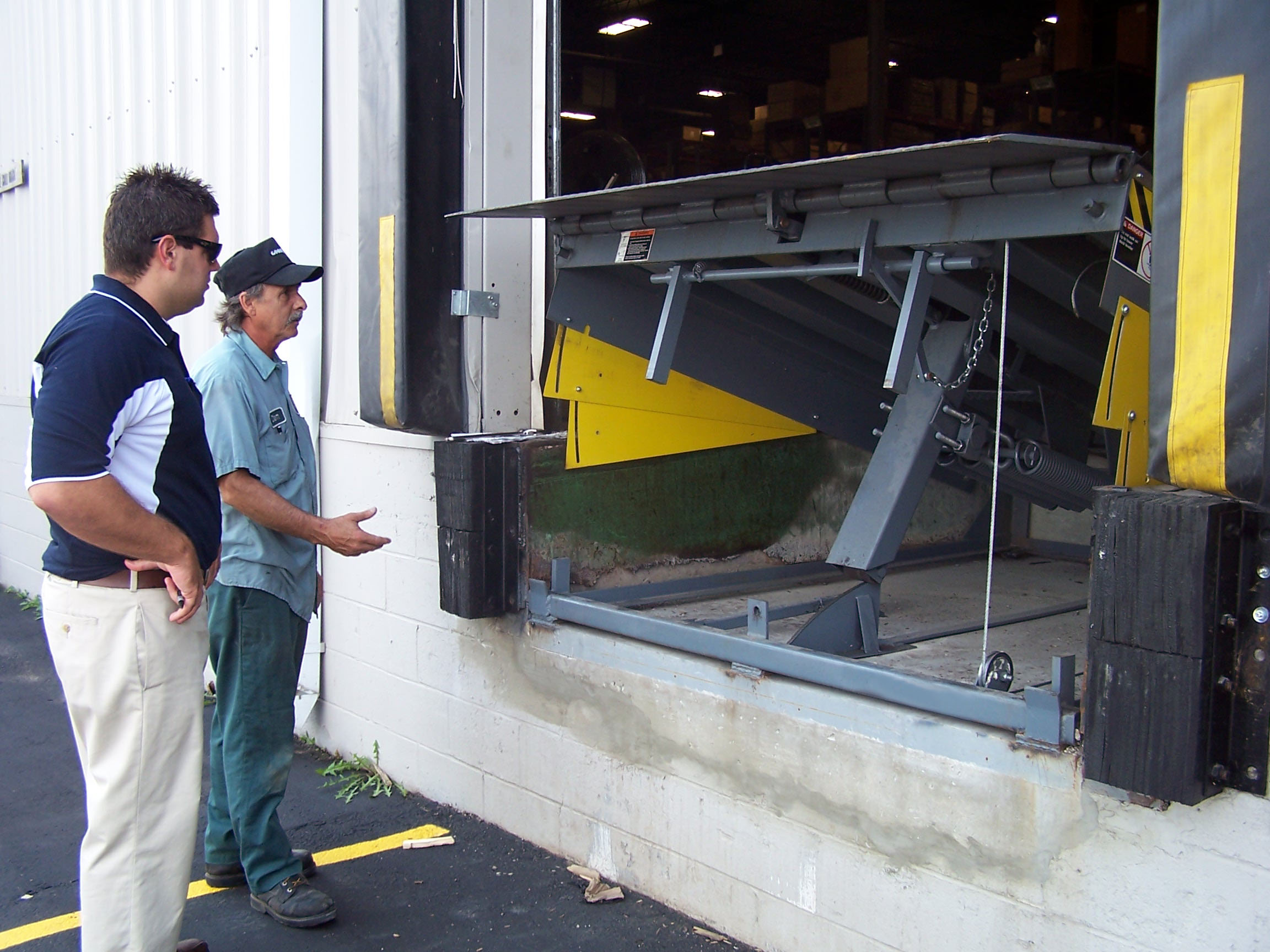 McKee service techs inspecting a loading dock leveler for an overhead door garage bay